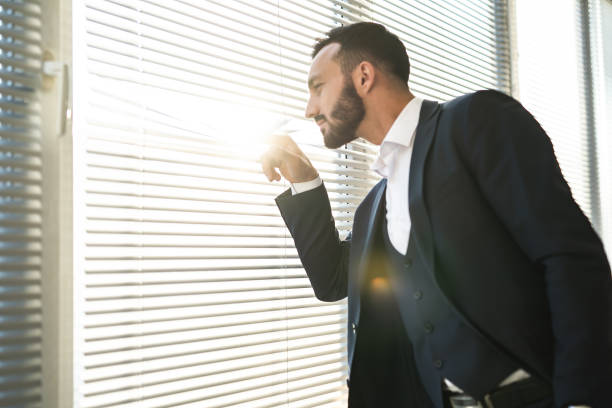 istock The businessman looking through the blinds on the window 1090124450