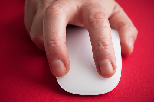 closeup of hand of man on white mouse on red background