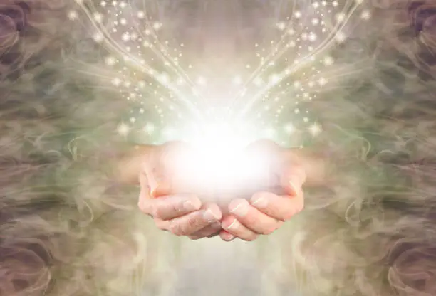 female cupped hands emerging from a green gold swirling energy field background with shimmering sparkles and white light flowing outwards
