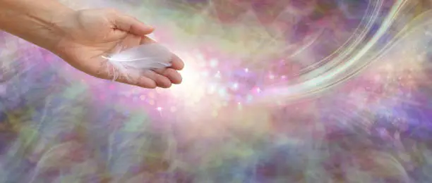 female open palm hand with a single white feather against a flowing ethereal multicoloured wide background