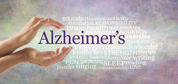 female hands gently cupped around the word ALZHEIMER'S and a relevant word cloud on a pale rustic   background