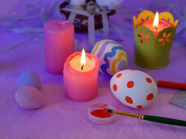 istock Easter decor, painted eggs, paints, brushes, lighted pink candles on a lilac background, preparation for the Easter holiday 1090131346