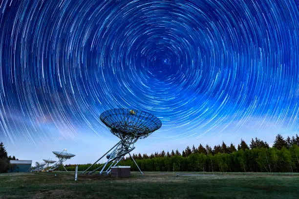 Radar at night, with a dark blue sky, stars and startrails. Westerbork Synthesis Radio Telescope (WSRT).