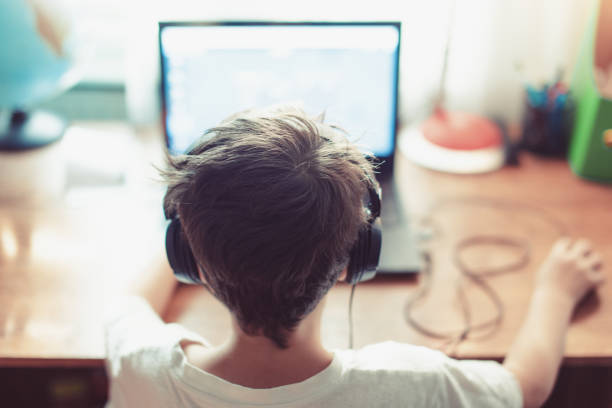 Little dependent gamer kid playing on laptop Little dependent gamer kid playing on laptop indoors nerd kid stock pictures, royalty-free photos & images