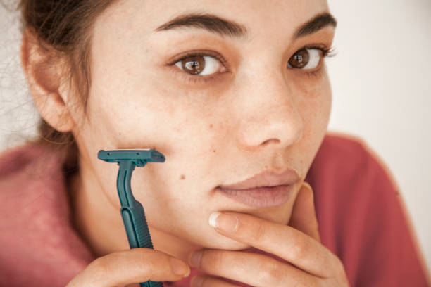 Young woman shaving beard on white background Young woman shaving beard on white background facial hair stock pictures, royalty-free photos & images