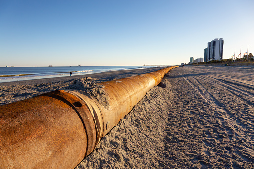Myrtle Beach, South Carolina, United States - October 29, 2018: Old Rusty Pipes on the sandy beach during a sunny sunset.