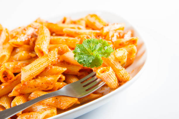 Penne with pesto decorated with parsley on a plate eaten with a fork on a white background