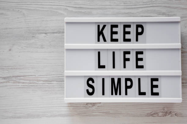 Lightbox with text 'Keep life simple'  over white wooden background, top view. Flat lay, from above. Copy space.