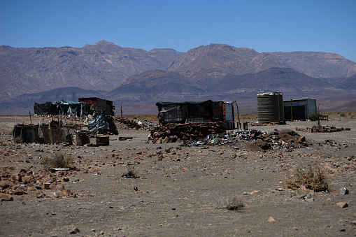 The mine is worked by just a few miners, who dig by hand. The shacks are shown in the centre of the photo, and reveal the extreme poverty and isolation that the miners live in. Mountains are shown in the distance. \n\nGobogobos is an area west of Brandberg Mountain in the Erongo region of Namibia. The area is famous for its crystals. The photo was taken in February 2018.