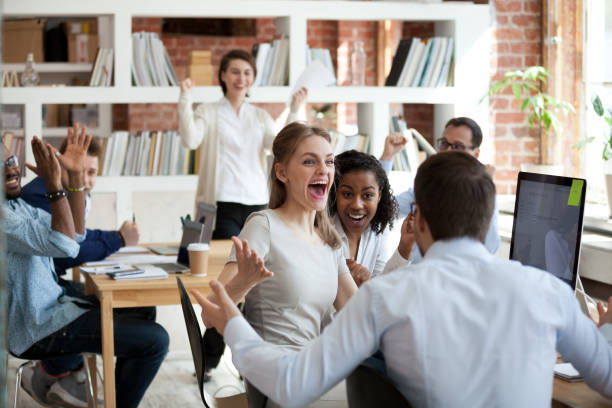 Excited diverse business team employees screaming celebrating good news success Excited diverse business team employees screaming celebrating good news business win corporate success, happy multi-ethnic colleagues workers group feeling motivated ecstatic about great achievement sales win stock pictures, royalty-free photos & images