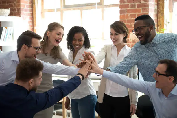 Photo of Happy diverse colleagues give high five together celebrate great teamwork