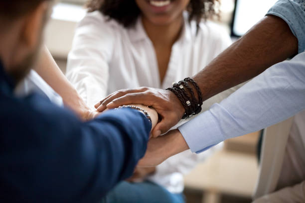 Diverse business people put hands together in pile, support concept