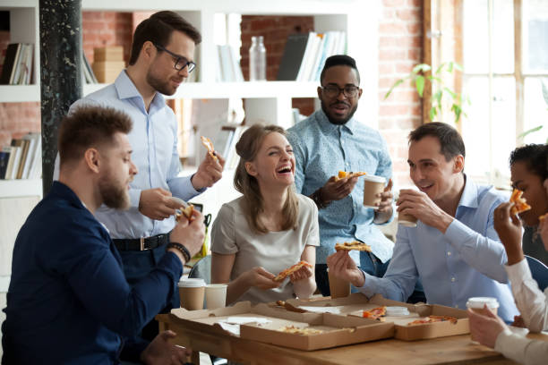 istock Happy diverse team people talking laughing eating pizza in office 1090216764