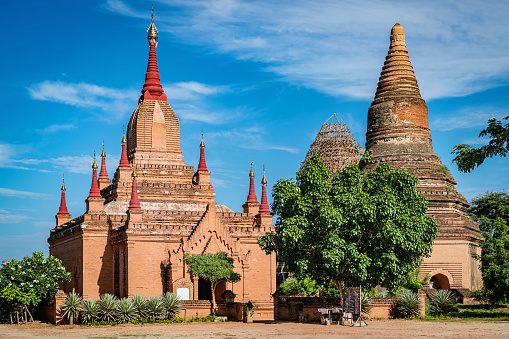 Mee Nyein Gone Phaya Temple with Red Stupas and Ta Wa Gu Pagoda Temple Complex under blue summer sky. The Mee Nyein Gone Temple, built in the 12th century, is south of Bagan City. The name \