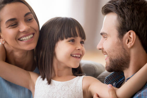 istock Happy kid daughter embracing parents looking at smiling mom 1090217366