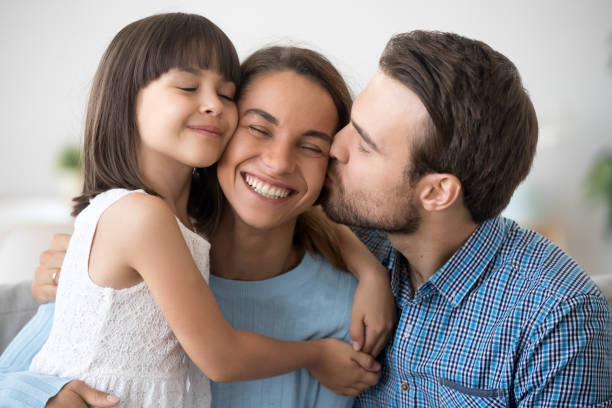 marito amorevole e figlia carina che abbraccia baciare la donna felice - wife father mother offspring foto e immagini stock