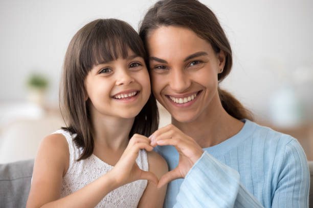 fille mignonne et heureuse mère joignent les mains en forme de coeur - family child portrait little girls photos et images de collection