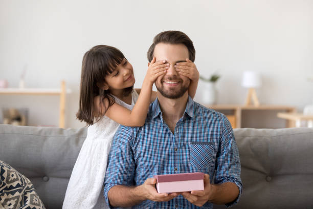 istock Cute kid daughter making surprise to dad receiving gift box 1090217590