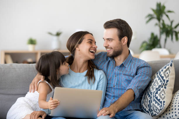 istock Happy family of three bonding using laptop sitting on couch 1090217614