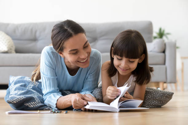 madre solícita lectura con niño niña en casa - togetherness learning playful mother fotografías e imágenes de stock