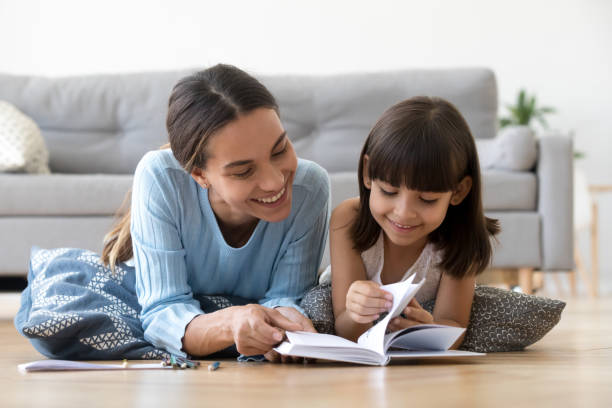 caring mother reading book with little kid girl at home - child reading mother book imagens e fotografias de stock