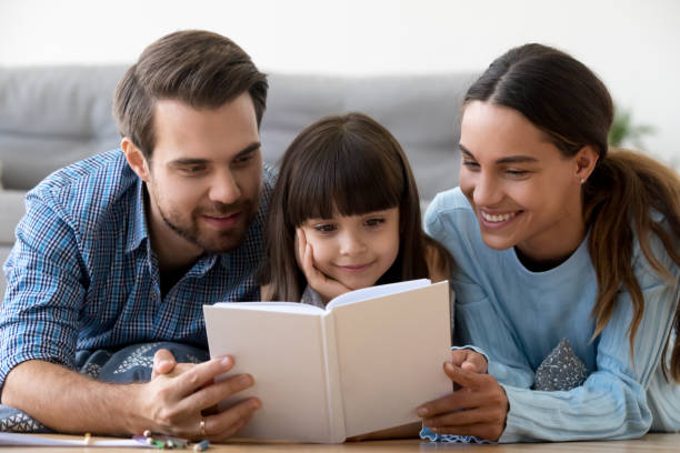 mama i tata z małą uroczą córką czytając razem książkę - child reading mother book zdjęcia i obrazy z banku zdjęć
