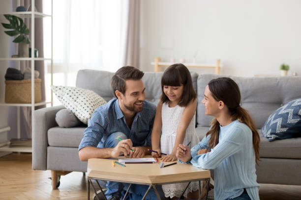 Caring mom and dad teaching little daughter to draw