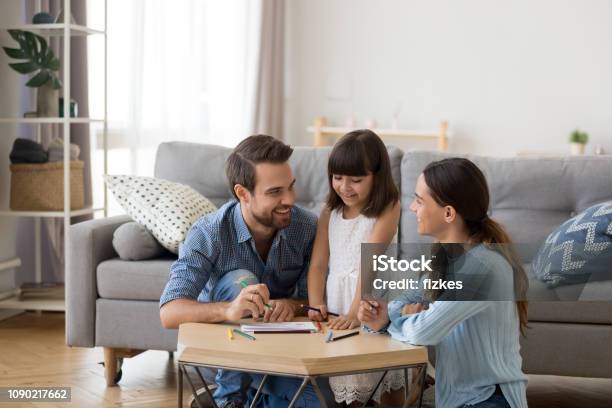 Caring Mom And Dad Teaching Little Daughter To Draw Stock Photo - Download Image Now