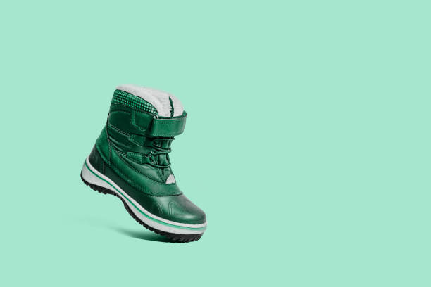 istock A green children's shoe on a green, pastel background. 1090224116