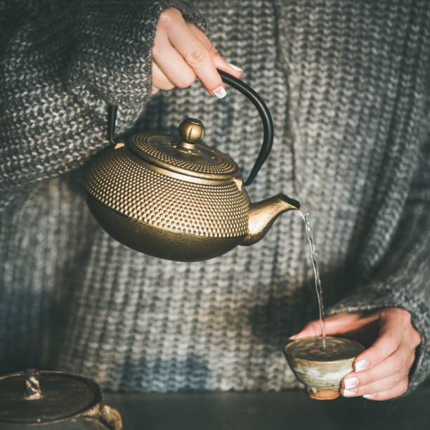 istock Female pouring green tea from pot into cup, square crop 1090232886