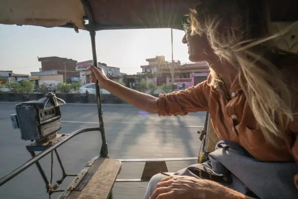 Young woman riding on rickshaw in India traveling and discovering the country, town in Jaipur, India, Southeast Asia. People travel sharing communication concept