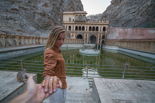 Follow me to monkey temple, India. Female tourist leading boyfriend to the sacred place. People travel concept