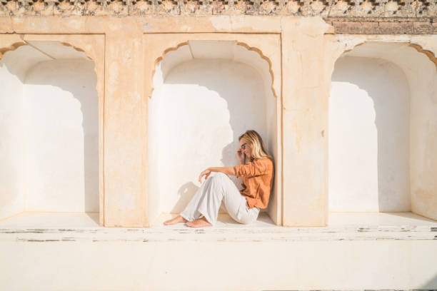 молодая женщина, путешествующая по индии, посещает храм, сидя на окне, созерцая архитектуру. люди путешествия открытие азии концепции. - jaipur city palace стоковые фото и изображения