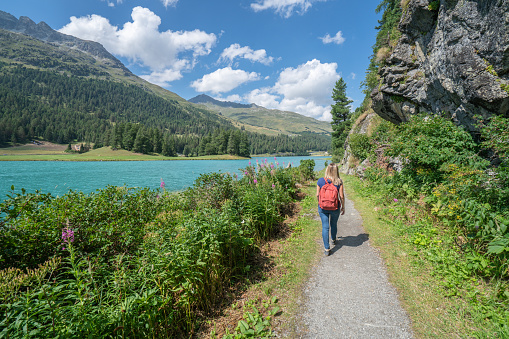 Young woman hiking and walking near mountain lake