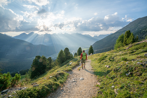 Hiker male hiking down trail in beautiful nature environment in the Swiss alps