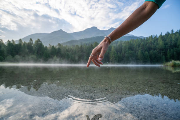 istock Finger touches surface of mountain lake, Switzerland 1090245708
