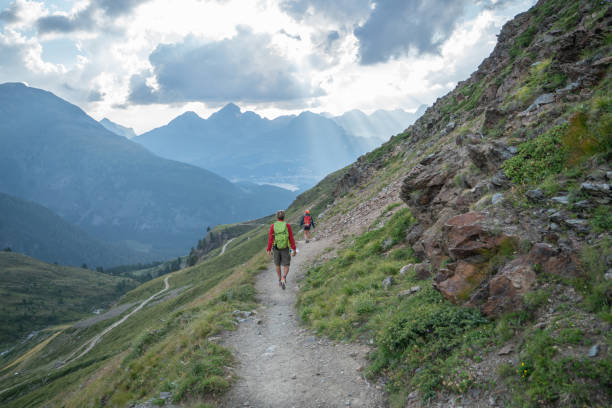 istock Two hikers walking down the mountain trail in Summer at sunset 1090247332