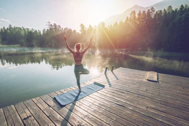 istock Woman practicing yoga poses in nature, lake pier 1090247708