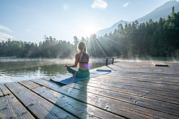 femme pratiquant le yoga pose dans la nature, jetée de lac - st moritz mountain nature water photos et images de collection