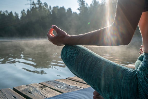entspannendes yoga in der natur-nahaufnahme am körper der frau, der lotusposition am seesteg bei sonnenaufgang hält - st moritz fotos stock-fotos und bilder