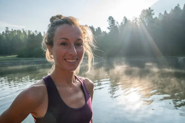 Portrait of young woman on lake pier at sunrise. People wellbeing relaxation healthy lifestyle concept.
Shot in Graubunden Canton, Switzerland.