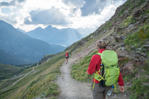 istock Two hikers walking down the mountain trail in Summer at sunset 1090260206