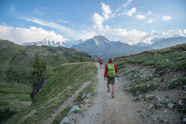 istock Two hikers walking down the mountain trail in Summer at sunset 1090260208