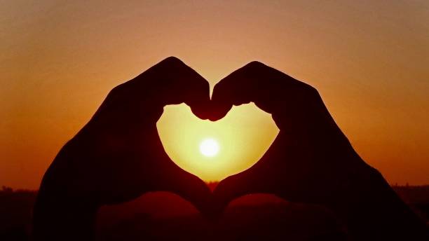 istock Close-Up Of Hands Making Heart Shape Against Sun In Sky During Sunset 1090260450