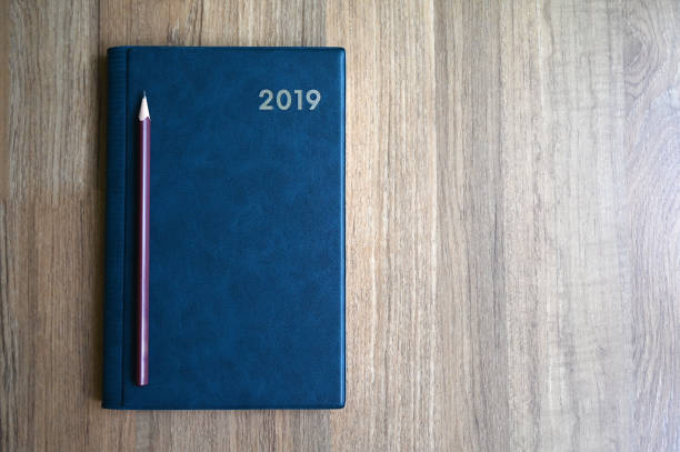 istock Blue notebook with number 2019 and pencil on wooden table with copy space for text or product display. 1090262364