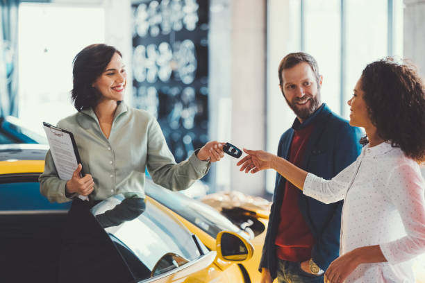 Woman enjoying a new car Young man surprising his wife with buying a new car showroom photos stock pictures, royalty-free photos & images