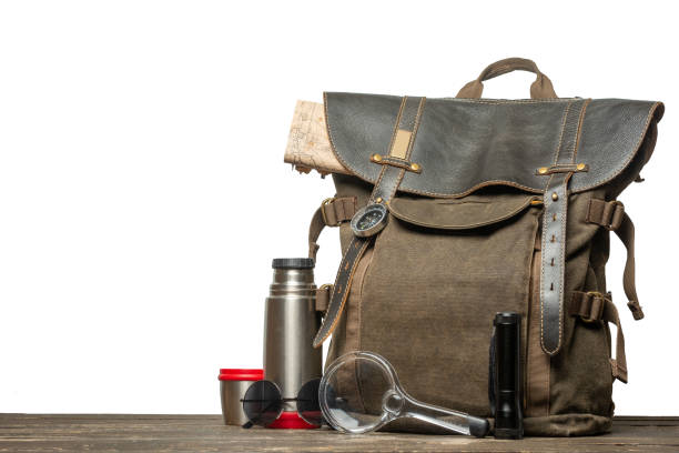 istock Vintage brown backpack with tourism accessories on a table with an isolated background. 1090274090