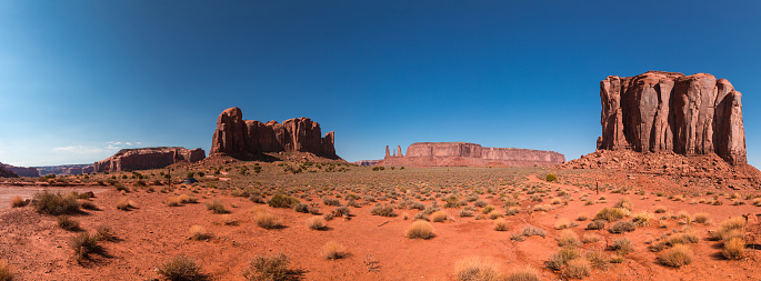 Monument Valley, a red-sand desert region on the Arizona-Utah border, is known for the towering sandstone buttes of Monument Valley Navajo Tribal Park. Monument valley landscape with buttes.