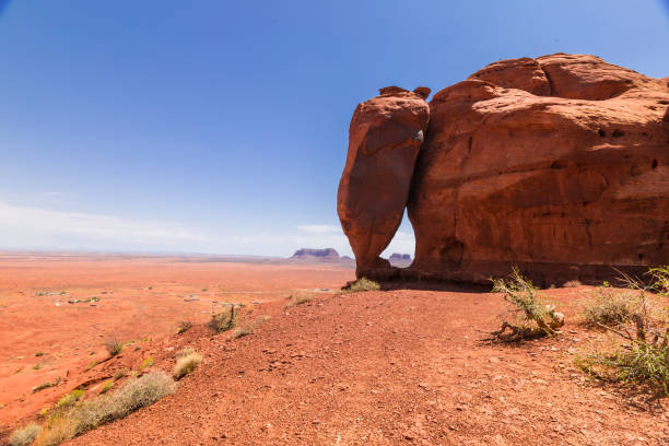 Monument Valley, a red-sand desert region on the Arizona-Utah border, is known for the towering sandstone buttes of Monument Valley Navajo Tribal Park. Teardrop Arch at Monument valley landscape with buttes.