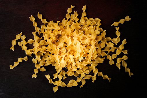 Close up photograph of dry ribbon pasta against dark background